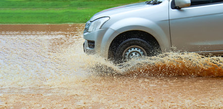 Floodwater splashing violently caused by a vehicle which are driven through, capturing the raw intensity of the natural disaster.の写真素材