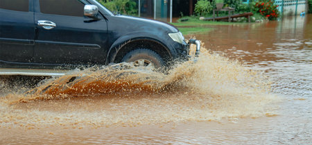 Floodwater splashing violently caused by a vehicle which are driven through, capturing the raw intensity of the natural disaster.の写真素材