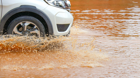 Floodwater splashing violently caused by a vehicle which are driven through, capturing the raw intensity of the natural disaster.の写真素材