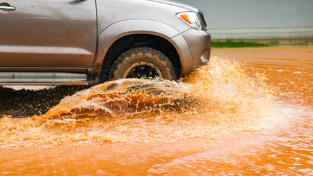 Floodwater splashing violently caused by a vehicle which are driven through, capturing the raw intensity of the natural disaster.の写真素材