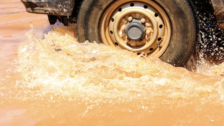 Floodwater splashing violently caused by a vehicle which are driven through, capturing the raw intensity of the natural disaster. Vehicle Insurance conceptの写真素材