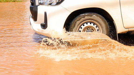 Floodwater splashing violently caused by a vehicle which are driven through, capturing the raw intensity of the natural disaster. Vehicle Insurance conceptの写真素材
