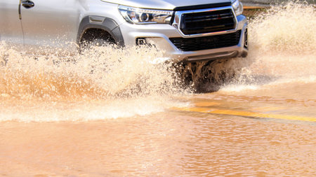 Floodwater splashing violently caused by a vehicle which are driven through, capturing the raw intensity of the natural disaster. Vehicle Insurance conceptの写真素材