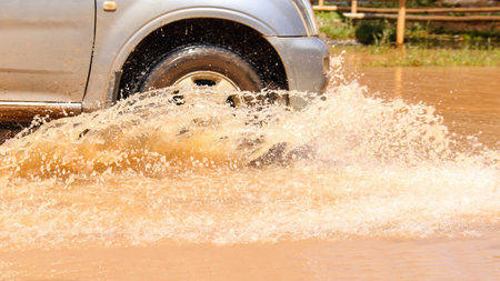 Floodwater splashing violently caused by a vehicle which are driven through, capturing the raw intensity of the natural disaster. Vehicle Insurance conceptの写真素材