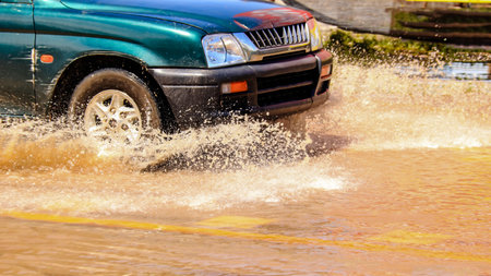 Floodwater splashing violently caused by a vehicle which are driven through, capturing the raw intensity of the natural disaster. Vehicle Insurance conceptの写真素材