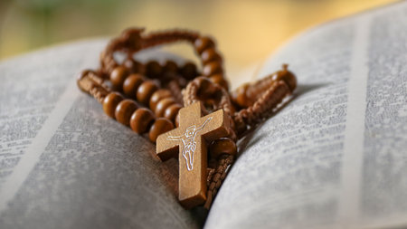 Dark brown wooden cross on an old open book, symbolizing the spread of love among Christians, reflecting faith, devotion, and the importance of Christian teachings.の写真素材