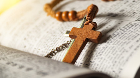 Dark brown wooden cross on an old open book, symbolizing the spread of Jesus Christâs love among Christians, reflecting faith, devotion, and the importance of Christian teachings.の写真素材
