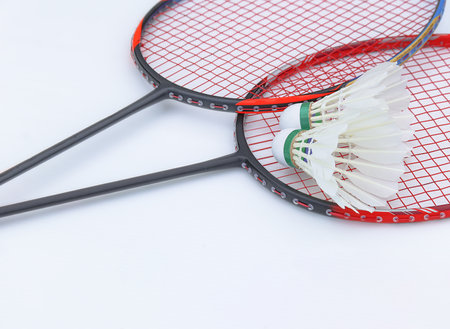 White shuttlecock made of feathers resting on badminton rackets, set against white background, representing the concept of exercise for good health and youth badminton competitions.の写真素材
