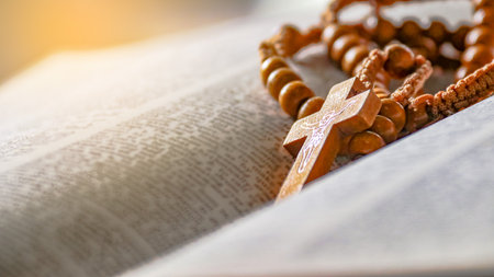 Dark brown wooden cross on an old open book, symbolizing the spread of Jesus Christâs love among Christians, reflecting faith, devotion, and the importance of Christian teachings.の写真素材