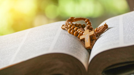 Dark brown wooden cross on an old open book, symbolizing the spread of Jesus Christâs love among Christians, reflecting faith, devotion, and the importance of Christian teachings.の写真素材