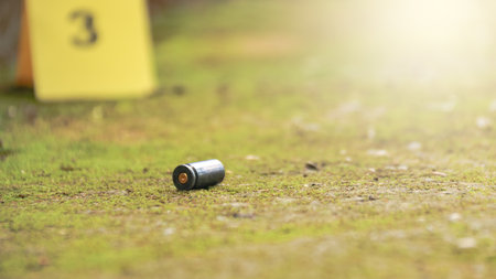 Spent bullet casing lying on the ground with blur number 3 sign. Concepts of shooting sports and security highlighting the dual nature of firearms in both competitive sport and protective measures.の写真素材