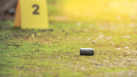 Spent bullet casing lying on the ground with blur number 2 sign. Concepts of shooting sports and security highlighting the dual nature of firearms in both competitive sport and protective measures.の写真素材