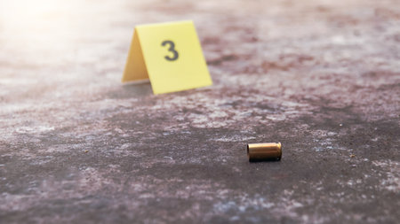 Spent bullet casing lying on the ground with blur number 3 sign. Concepts of shooting sports and security highlighting the dual nature of firearms in both competitive sport and protective measures.の写真素材