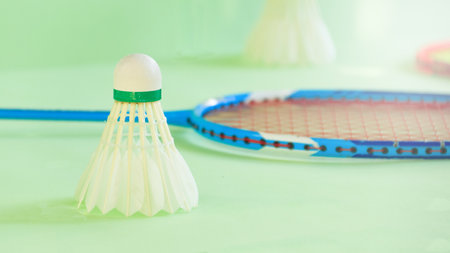 White badminton shuttlecocks and badminton rackets on green backgroundの写真素材