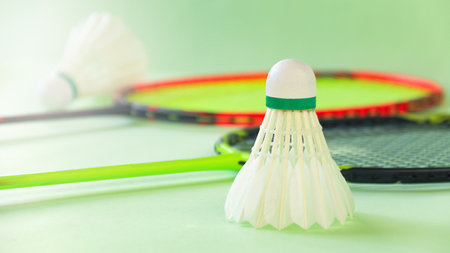 White badminton shuttlecocks and badminton rackets on green backgroundの写真素材
