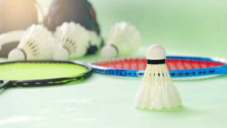 White badminton shuttlecocks and badminton rackets on green backgroundの写真素材