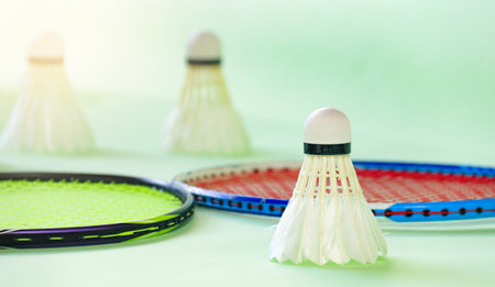 White badminton shuttlecocks and badminton rackets on green backgroundの写真素材