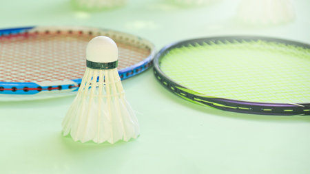 White badminton shuttlecocks and badminton rackets on green backgroundの写真素材