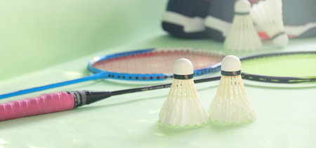 White badminton shuttlecocks and badminton rackets on green backgroundの写真素材