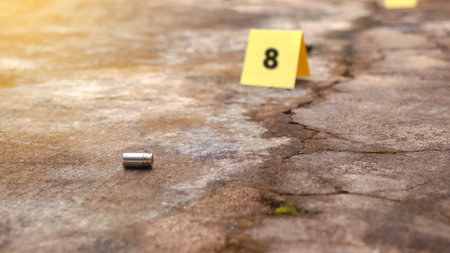 Spent bullet casing lying on the ground with blur number 8 sign. Concepts of shooting sports and security highlighting the dual nature of firearms in both competitive sport and protective measures.の写真素材