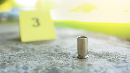 Spent bullet casing lying on dark ground with blur number 3 sign. Concepts of criminal investigationsの写真素材