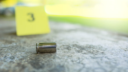 Spent bullet casing lying on dark ground with blur number 3 sign. Concepts of criminal investigationsの写真素材