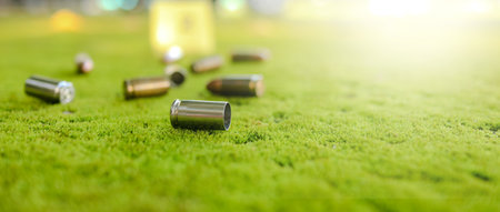 Spent bullet casing lying on the green ground with blur number 2 sign. Concepts of criminal investigation and shooting sportsの写真素材