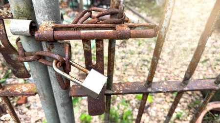 Shiny silver metal lock pad hooks onto an old, rusty chain, capturing the contrast between new and aged metal, symbolizing security, access, and the passage of time.の写真素材