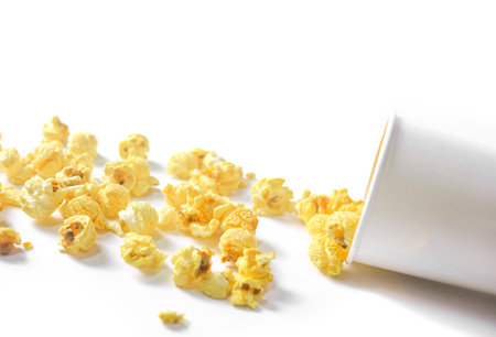 Isolated image of popcorn in paper cup set against a white background, showcasing the fluffy, golden kernels spilling over the edges, perfect for themes related to snacks, cinema, or casual dining.の写真素材