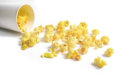 Isolated image of popcorn in paper cup set against a white background, showcasing the fluffy, golden kernels spilling over the edges, perfect for themes related to snacks, cinema, or casual dining.の写真素材