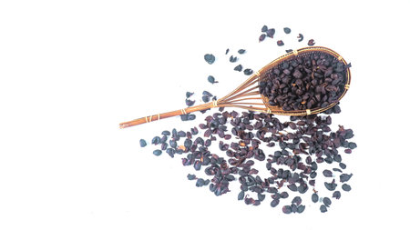 Isolated dark, dried coffee bean husks in bamboo basket and on a white background, highlighting the rough texture and deep color, suitable for themes related to coffee production and processing.の写真素材
