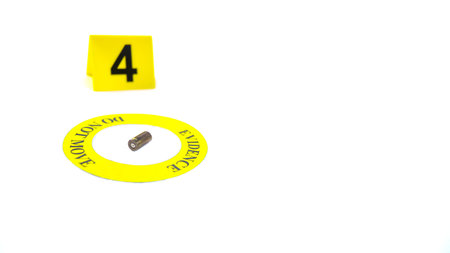 A spent bullet casing placed within a yellow circle, labeled with the text "Evidence, Do Not Move," with a blurred number 4 tag, set against a white background, concept of crime investigation.の写真素材