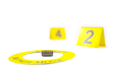 A spent bullet casing placed within a yellow circle, labeled with the text Evidence, Do Not Move, with a blurred number 4 and 2 tag, set against a white background, concept of crime investigation.の写真素材
