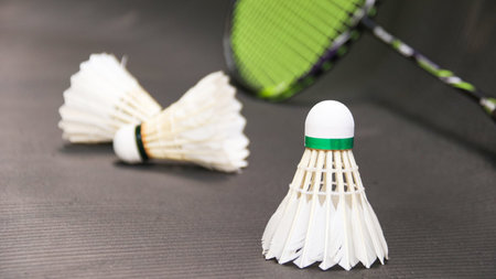 White badminton shuttlecocks and badminton rackets on dark backgroundの写真素材