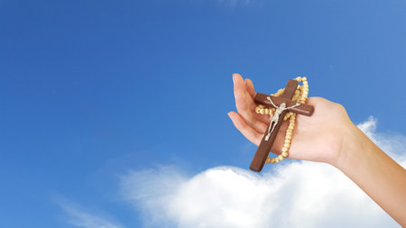 Brown wooden cross holding in hand, symbolizing, recalling and spreading of Jesus Christs love to all Christiansの写真素材
