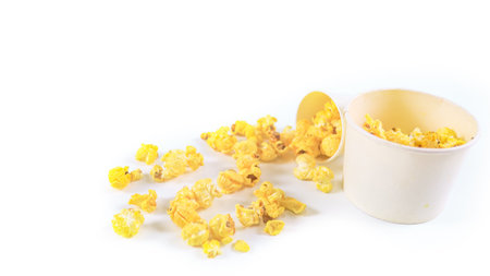 Isolated image of popcorn in paper cup set against a white background, showcasing the fluffy, golden kernels spilling over the edges, perfect for themes related to snacks, cinema, or casual dining.の写真素材