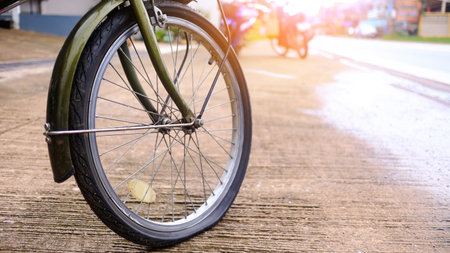 Flat tire wheel of bicycle parking on concrete sidewalk beside a road, need to be repaired, the moment of stillness and an unexpected pause in a journey.の写真素材