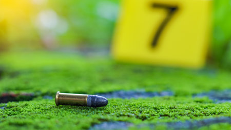 Empty bullet casing on a mossy surface, with a blurred black number 7 in the background, evoking the concept of crime scene investigation and unraveling mysteries.の写真素材