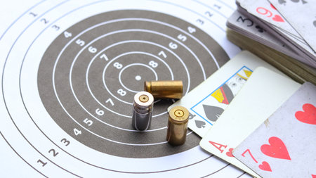 Empty bullet casings on a shooting target background, with playing cards placed nearby, blending the themes of marksmanship, chance in an unusual composition and bet crime.の写真素材