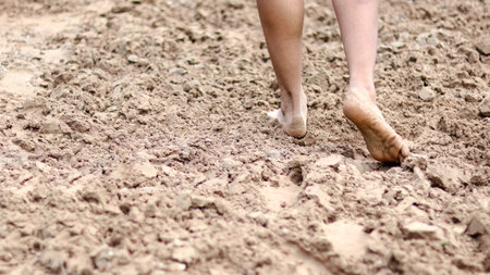 Bare feet walking on sandy ground, symbolizing the idea of healing, promoting both physical and mental well being through grounding and connection with nature.の写真素材