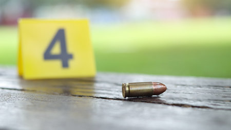 9 mm pistol copper head bullet lying on dark wooden bench with blur number 4 sign on blur background. Concepts of criminal investigations and shooting sport.の写真素材