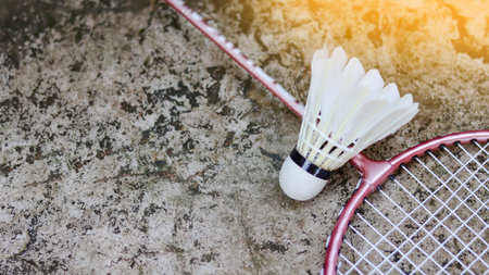 White badminton shuttlecocks and badminton rackets on dark background to enhance doing exercise.