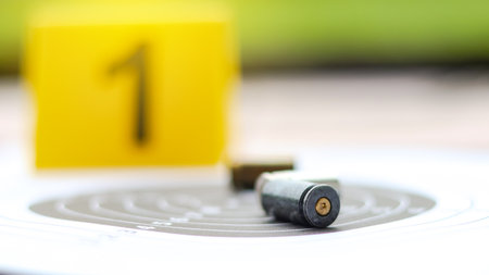 Empty bullet casing on a shooting target, with a blurred black number 1 in the background, evoking...