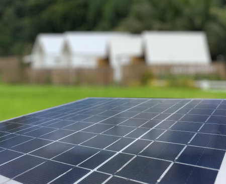 Solar panels set against a backdrop of resident, trees and a vibrant blue sky. The scene captures the harmony between renewable energy and nature, highlighting sustainability and environmental consciousness.の写真素材