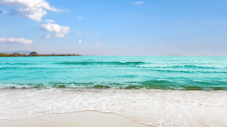 Stunning view of azure ocean waves gently crashing onto a pristine sandy beach, evoking a sense of relaxation and escape. The image conveys the idea of a perfect vacation by the sea.の写真素材
