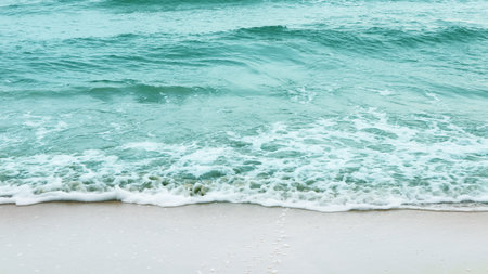 Stunning view of azure ocean waves gently crashing onto a pristine sandy beach, evoking a sense of relaxation and escape. The image conveys the idea of a perfect vacation by the sea.の写真素材