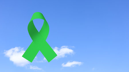 Hand holding green ribbon, symbolizing ovarain cancer awareness. Ribbon represents hope and unity, raising awareness and support for those affected by cancer, fostering understanding and prevention.の写真素材