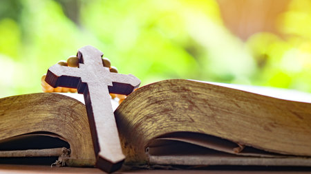 Brown wooden cross on an old open book symbolizing the spread of Jesus Christs love among Christians reflecting faith devotion and the importance of Christian teachings.の写真素材