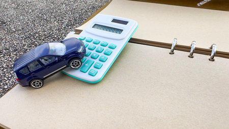 Model car and calculator are on notebook with blur background. Planning of saving for buying car, car loan and car insurance concept.の写真素材