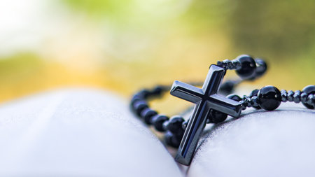 Dark metal cross on an old open book symbolizing the spread of Jesus Christs love among Christians...
